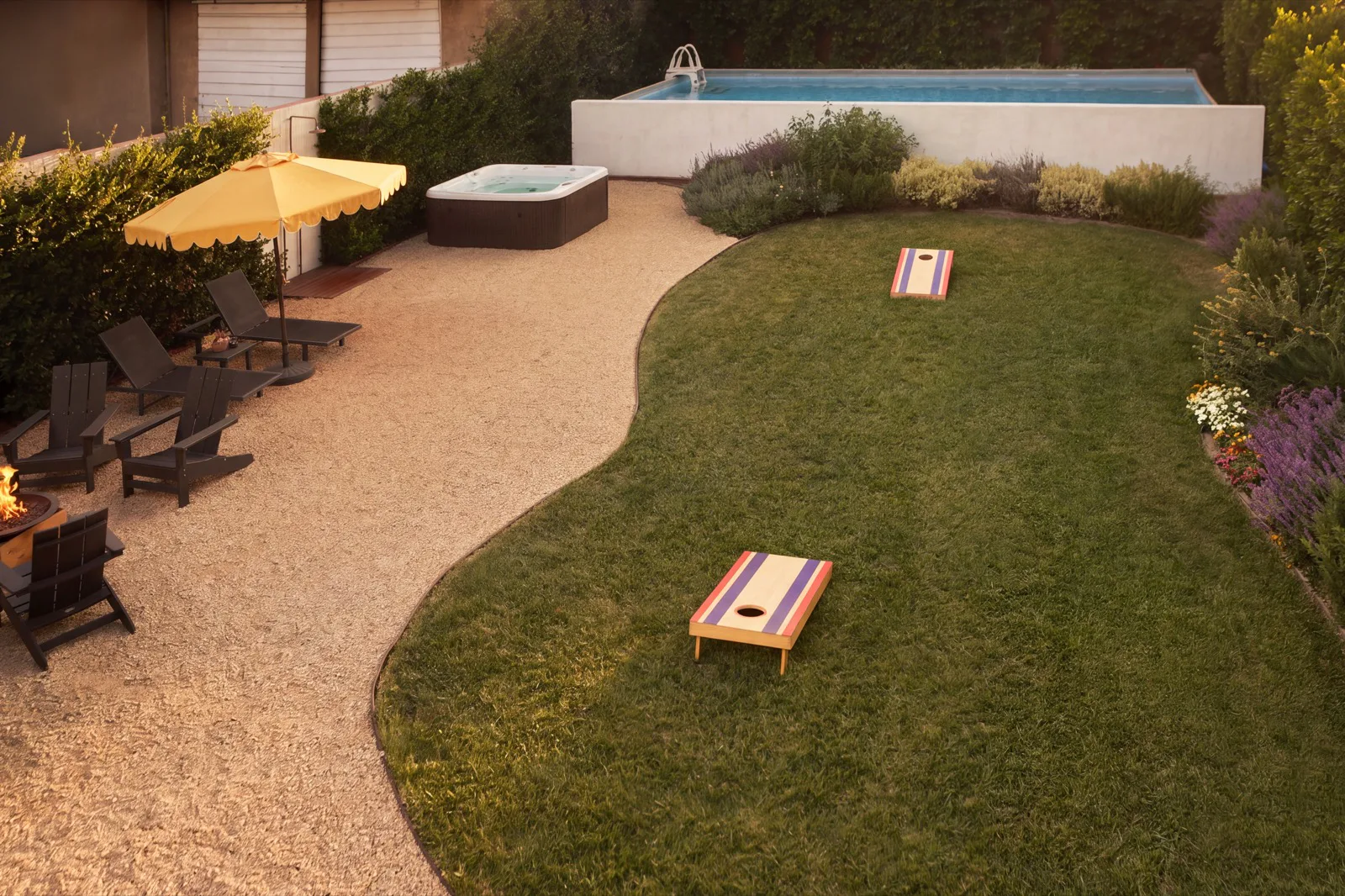 The private backyard at Casa Blanco at golden hour — saltwater pool, hot tub, fire pit and lawn